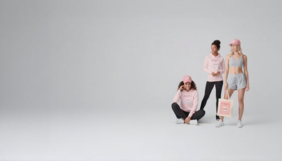 Three women wearing pink and gray athletic wear with a tote bag on a light gray background
